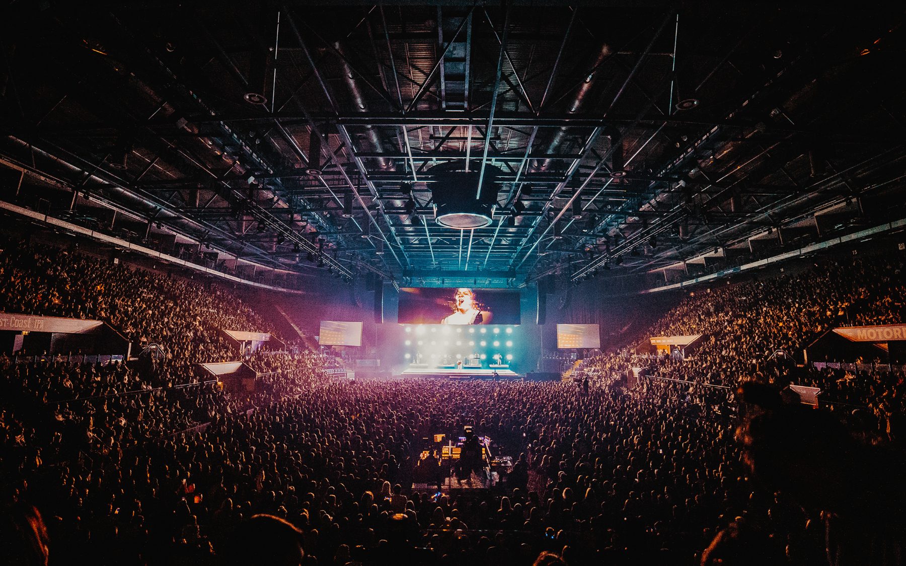 A packed arena crowd facing a lit stage